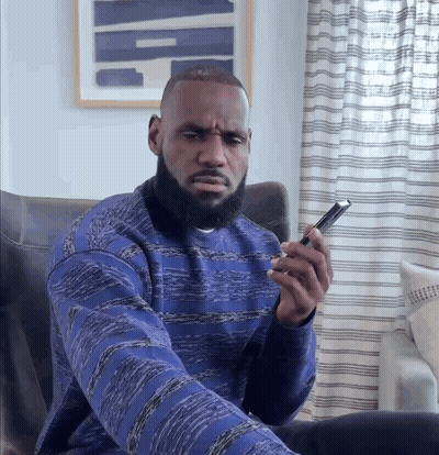 A Man In A Blue Sweater Is Looking At His Phone GIF