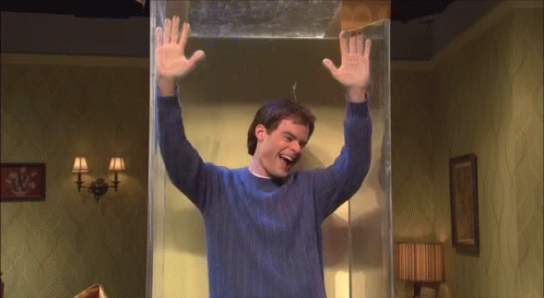 A Man In A Blue Sweater Is Standing In A Room With His Arms Up GIF