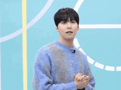 A Man In A Blue Sweater Is Standing In Front Of A Blue Background GIF