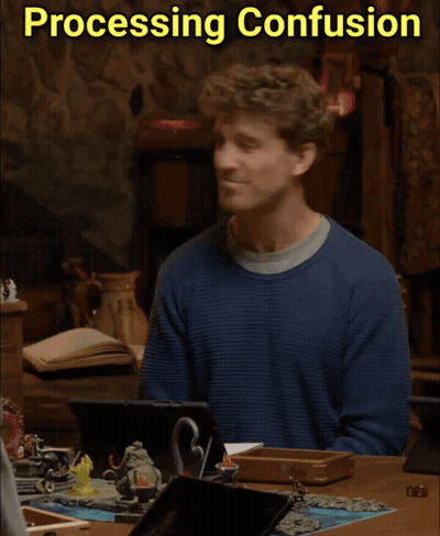A Man In A Blue Sweater Sits At A Table With Processing Confusion Written On The Bottom GIF