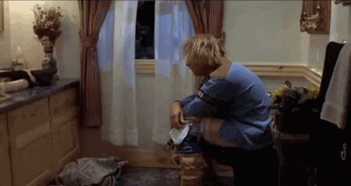 A Man In A Blue Sweater Sits On A Toilet GIF