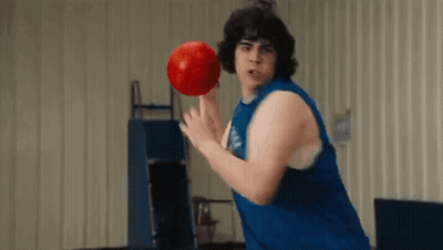 A Man In A Blue Tank Top Is Holding A Red Bowling Ball . GIF