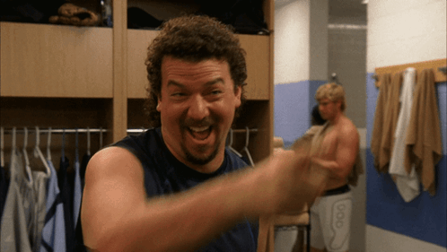 A Man In A Blue Tank Top Is Laughing In A Dressing Room GIF