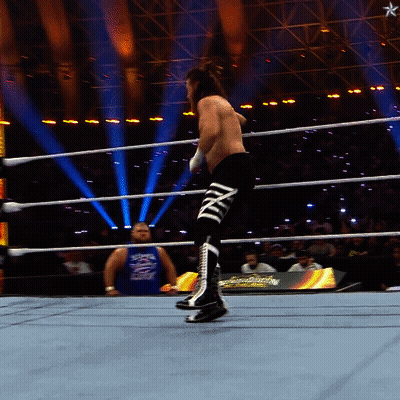 A Man In A Blue Tank Top With The Word Smackdown On It Stands In A Wrestling Ring GIF