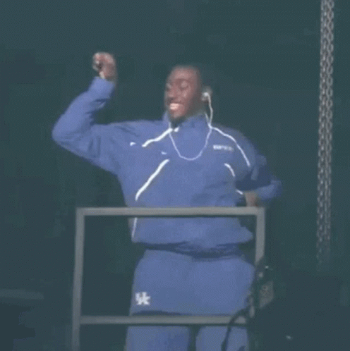 A Man In A Blue Tracksuit Is Dancing On A Stage . GIF