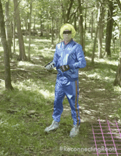 A Man In A Blue Tracksuit Is Standing In The Woods With The Hashtag #Reconnectingroots GIF