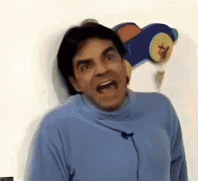 A Man In A Blue Turtleneck Sweater Is Making A Funny Face . GIF