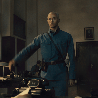 A Man In A Blue Uniform Is Standing In Front Of A Black Telephone GIF