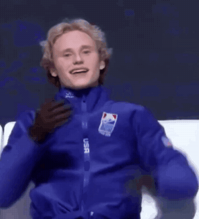 A Man In A Blue Usa Jacket Covering His Mouth With His Hand GIF