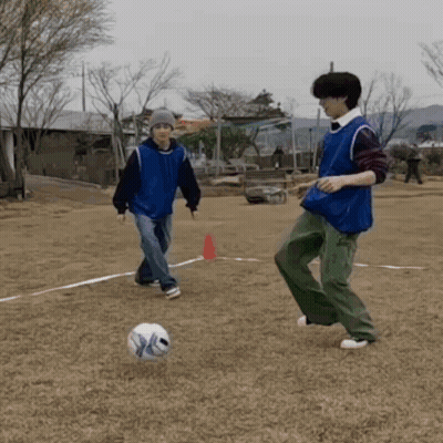 A Man In A Blue Vest Is Kicking A Soccer Ball While Another Man Watches GIF