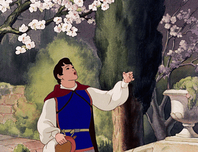 A Man In A Blue Vest Is Looking Up At A Tree GIF