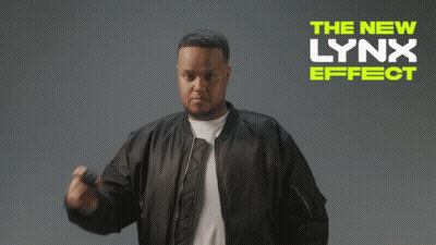 A Man In A Bomber Jacket Is Standing In Front Of A Sign That Says The New Lynx Effect GIF