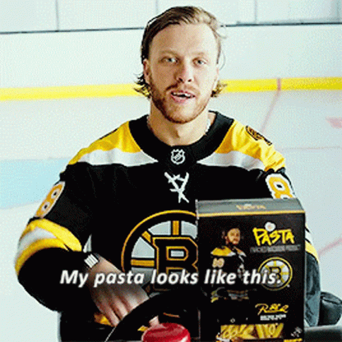 A Man In A Boston Bruins Jersey Is Sitting In Front Of A Box Of Pasta GIF