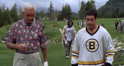 A Man In A Boston Bruins Jersey Is Standing On A Golf Course Next To A Man In A Floral Shirt . GIF
