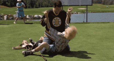 A Man In A Boston Bruins Jersey Is Wrestling Another Man In A Golf Course . GIF