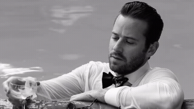 A Man In A Bow Tie Is Holding A Glass GIF