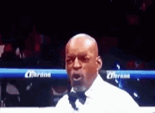 A Man In A Bow Tie Is Standing In A Boxing Ring . GIF