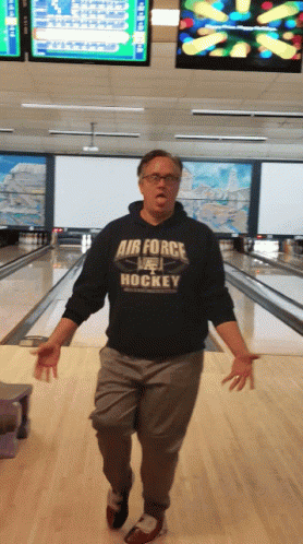 A Man In A Bowling Alley Wearing A Shirt That Says Air Force Hockey GIF