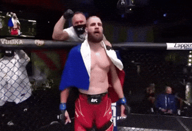 A Man In A Boxing Ring With A Flag Draped Over His Shoulder GIF