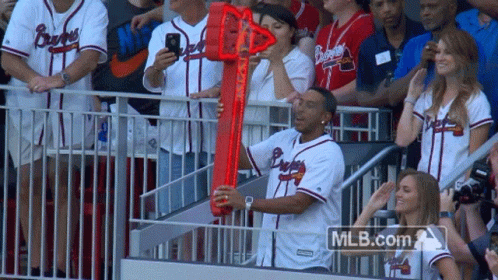 A Man In A Braves Jersey Holds A Red Object In Front Of A Crowd GIF