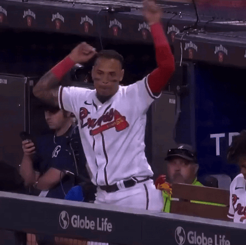 A Man In A Braves Jersey Stands In Front Of A Globe Life Sign GIF