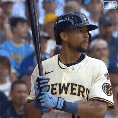 A Man In A Brewers Jersey Is Holding A Baseball Bat . GIF