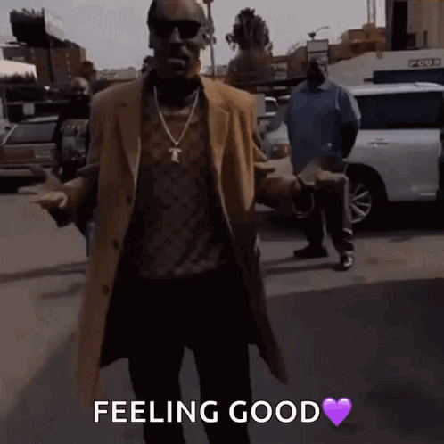 A Man In A Brown Coat Is Walking Down A Street With A Purple Heart And The Words Feeling Good Below Him GIF