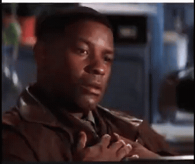A Man In A Brown Jacket And Tie Is Sitting At A Table With His Hands Folded . GIF