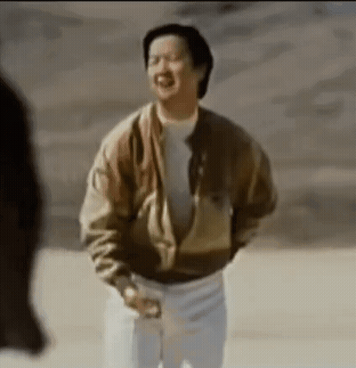 A Man In A Brown Jacket And White Pants Is Standing In A Desert . GIF