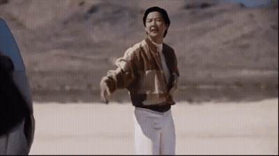 A Man In A Brown Jacket And White Pants Is Standing In A Desert . GIF