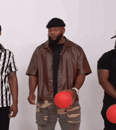 A Man In A Brown Jacket Holds A Red Ball In His Hand GIF
