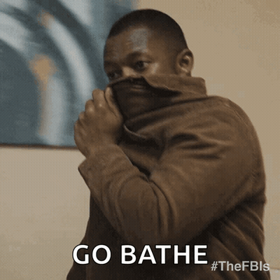 A Man In A Brown Jacket Is Covering His Face With His Jacket And Says Go Bathe GIF