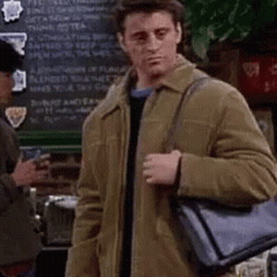 A Man In A Brown Jacket Is Holding A Black Bag And Asking What Are You Referring To My Man 'S Bag ? GIF