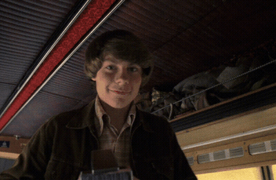 A Man In A Brown Jacket Is Holding A Can That Says ' 000000 ' On It GIF