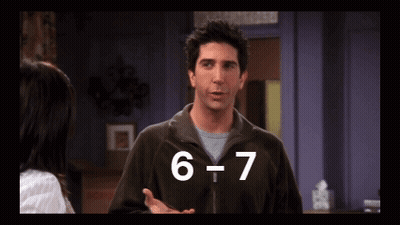 A Man In A Brown Jacket Is Talking To A Woman In A Room With The Number 6 And 7 Written On The Screen GIF