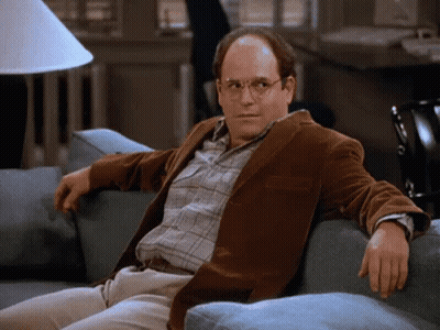 A Man In A Brown Jacket Sits On A Couch GIF