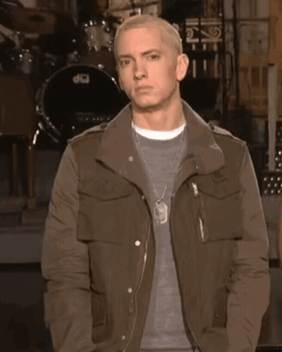 A Man In A Brown Jacket Stands In Front Of A Drum Set That Says Dw GIF