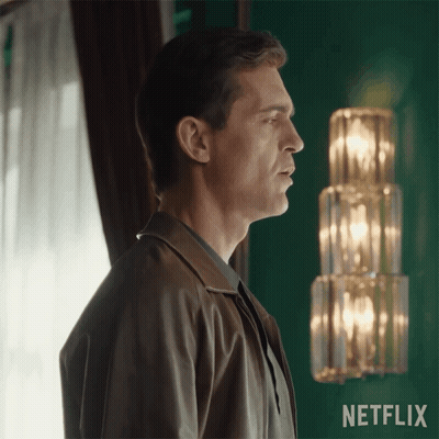 A Man In A Brown Jacket Stands In Front Of A Netflix Sign GIF