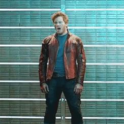 A Man In A Brown Leather Jacket Is Standing In Front Of A Brick Wall With His Mouth Open . GIF