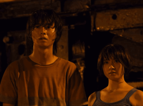 A Man In A Brown Shirt And A Woman In A Blue Tank Top Are Standing Next To Each Other GIF