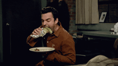 A Man In A Brown Shirt Is Eating A Sandwich And Drinking From A Bottle GIF