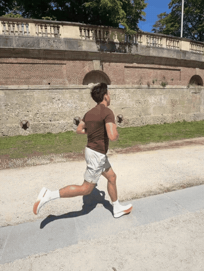 A Man In A Brown Shirt Is Running On A Road GIF