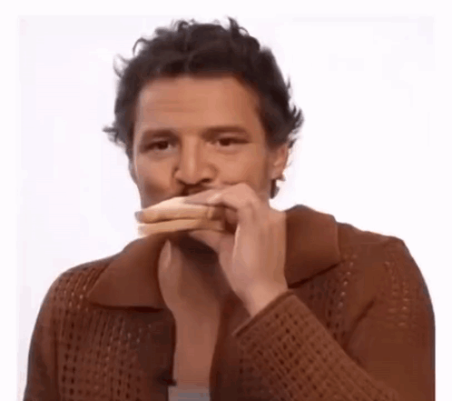 A Man In A Brown Sweater Is Eating A Sandwich With His Mouth Open . GIF
