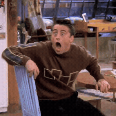 A Man In A Brown Sweater Is Sitting In A Chair With His Mouth Open . GIF