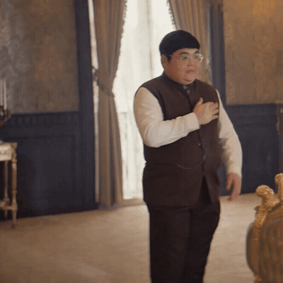 A Man In A Brown Vest And White Shirt Is Standing In A Room GIF