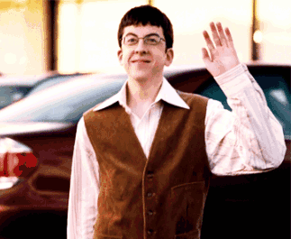 A Man In A Brown Vest And White Shirt Is Waving GIF