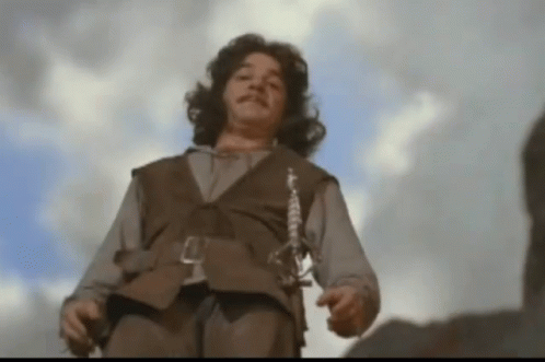 A Man In A Brown Vest With A Sword Around His Waist GIF