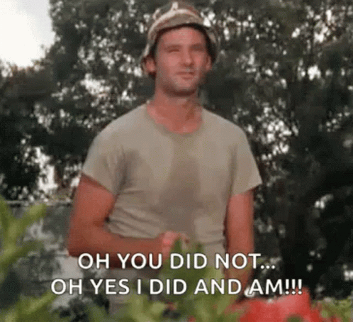 A Man In A Bucket Hat Is Standing In Front Of A Bunch Of Tomatoes And Tomatoes . GIF