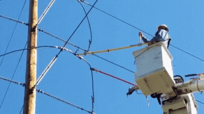 A Man In A Bucket Is Working On A Power Pole GIF