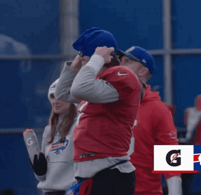 A Man In A Buffalo Bills Jersey Stands Next To Another Man GIF